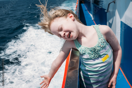 A little girl leans over the edge of a boat photo