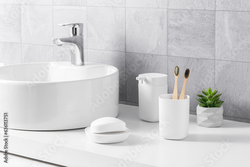 Modern bright bathroom interior with a white sink, bamboo toothbrushes, and a grey color porcelain floor tiles background, minimal style, close-up side view