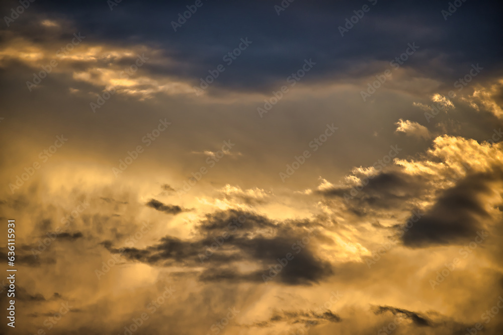 Fototapeta premium Sun casting long shadows and warm golden hue over clouds