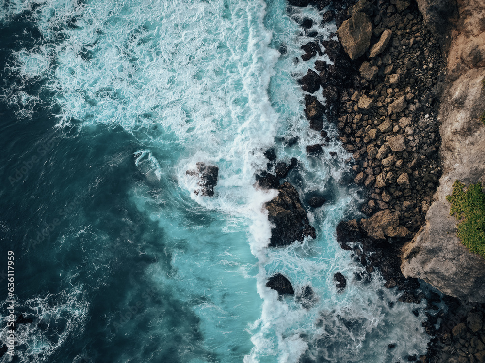 Fototapeta premium Top view of ocean waves crashing into big rocks