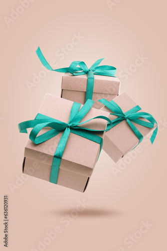 Christmas gift boxes with turquoise ribbon falling or flying in air with shadow on beige background.