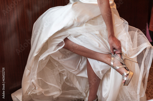 Bride getting dressed tying her bridal shoes