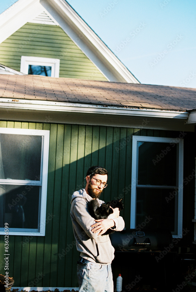 millennial man holding black cat in backyard outdoors millennial man holding black cat in backyard outdoors