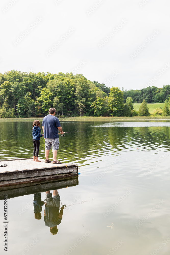 Father and daughter fishing off the end of a dock Father and daughter fishing off the end of a dock