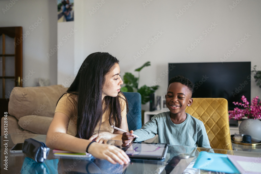 Babysitter with toddler doing his homework and drawing with a tablet Babysitter with toddler doing his homework and drawing with a tablet