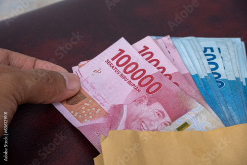 someone is removing Indonesian rupiah banknotes from the salary envelope