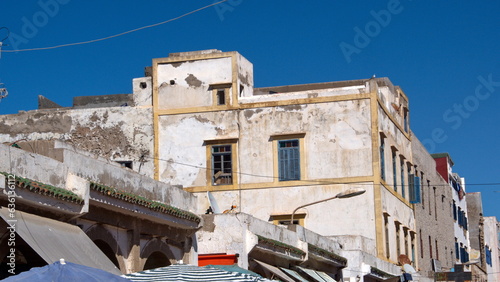 Old building with yellow trim and blue shutters above the market in Essaouira, Morocco © Angela