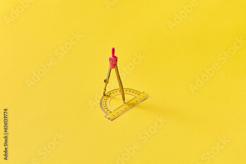 Pink compass and protractor on bright yellow background. photo