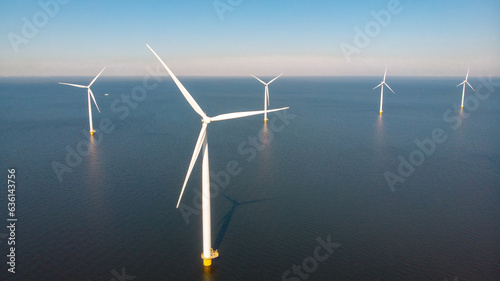 Drone Aerial view at Windmill park with windmills turbines in the ocean with a blue sky