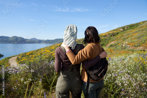 Two girls look out over a lake with their arms around each other