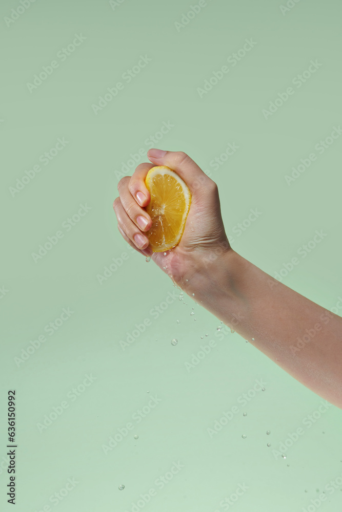 woman Hand Squeezing a Half fresh Lemon isolated on green background woman Hand Squeezing a Half fresh Lemon isolated on green background