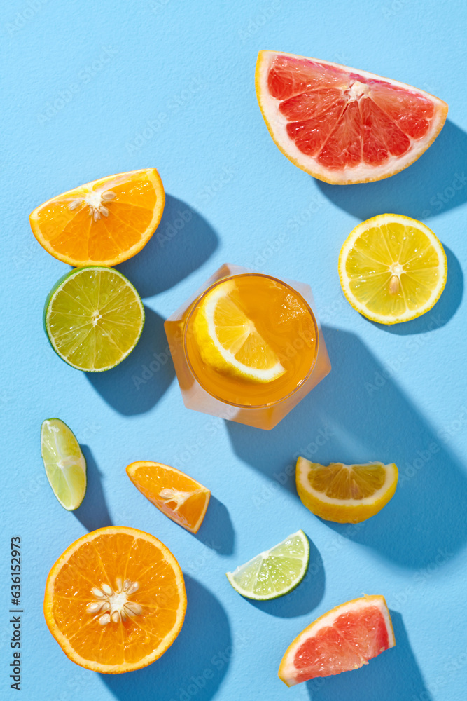Mix Citrus fruits with glass of juice over blue background Mix Citrus fruits with glass of juice over blue background