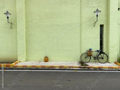 An old cycle kept in support to a wall at outdoors photo