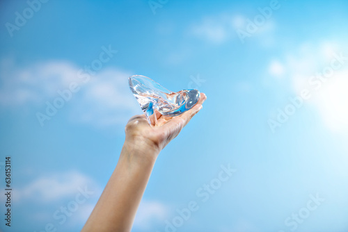 Crystal slipper on the palm of your hand on a cloud background photo