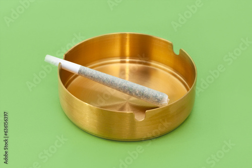 Cannabis preroll joint in a round gold ashtray 