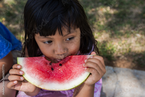 Girl sitting on curb eating a watermelon