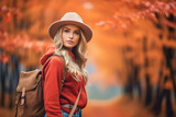 Portrait of young woman traveler in a stylish hat and warm clothes smiling and walking in nature in an autumn