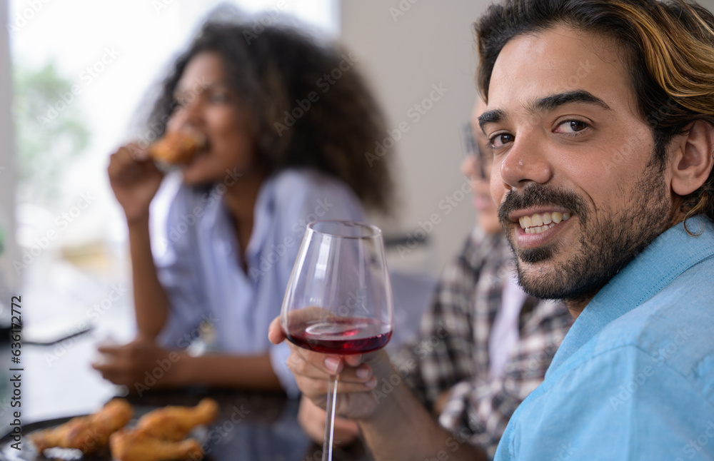 Portrait of smiling man holding glass of red wine while his friends sitting in background. Happy diversity people enjoying party at home
Portrait of smiling man holding glass of red wine while his friends sitting in background. Happy diversity people enjoying party at home