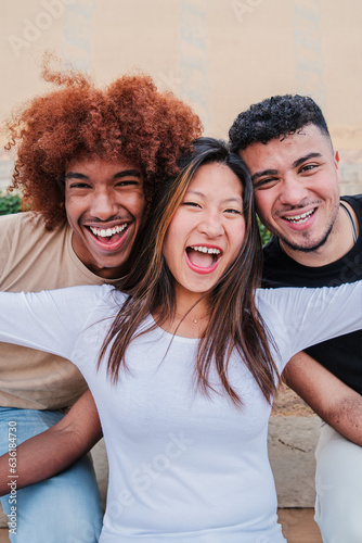 Vertical portrait of a group of multiracial teenagers laughing smiling together. Asian young woman spreading arms and having fun with her male friends. Happy and excited people bonding on a meeting