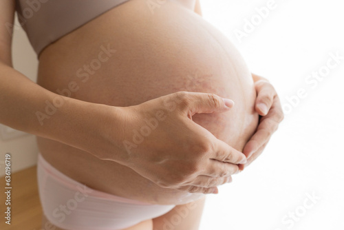 Pregnant woman in underwear who touches her belly 