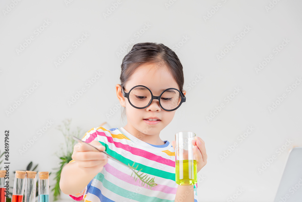 Asian little girl working with test tube science experiment in white classroom