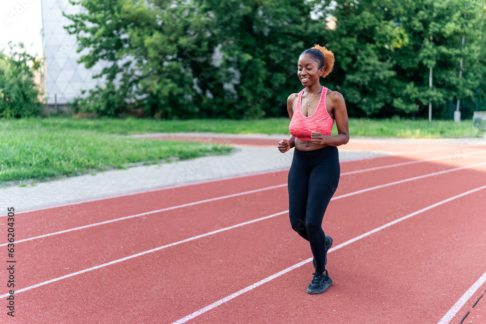 The confident black woman casually jogs on a running track, exuding grace and ease. Her relaxed stride inspires with its effortless beauty, showcasing her love for running