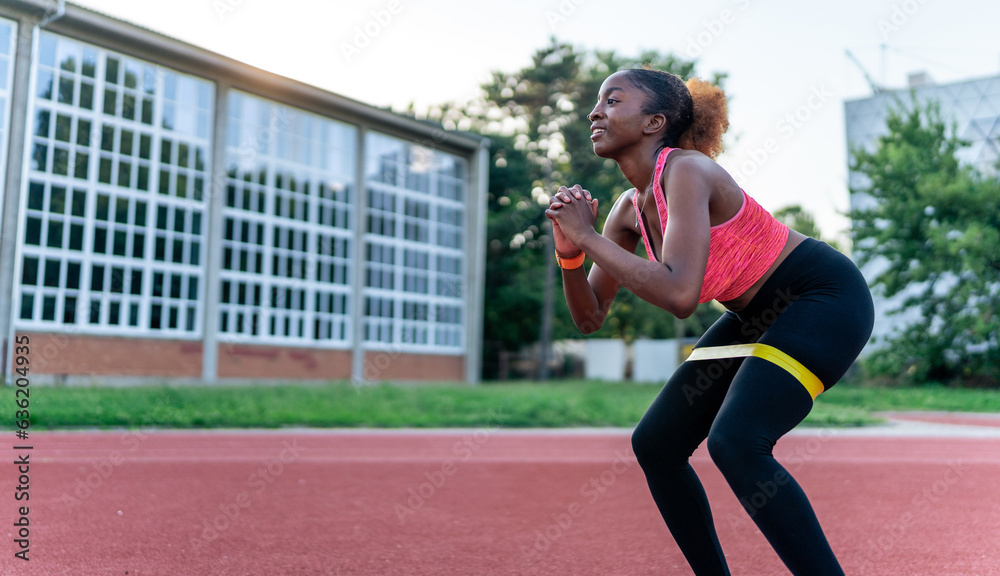 The black woman incorporates resistance bands into her training routine, leveraging their versatility for a challenging workout. With focused determination
