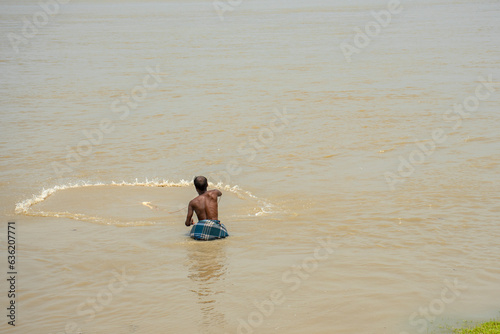 5th June, 2023, Burul, West Bengal, India: A fisherman throwing his fishing net at water for catching fish.