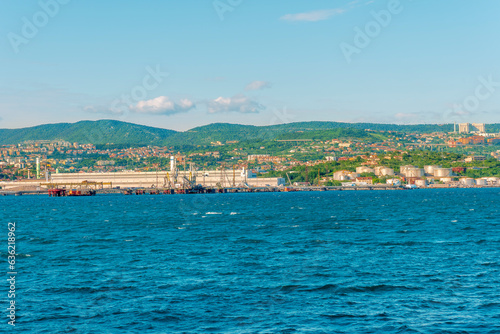 cargo sea port with cranes vehicles, container stacks , supplies and trucks with goods, sea hub terminal from seashore