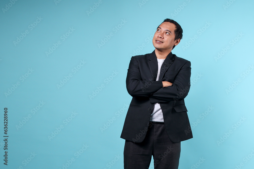 Portrait of Asian man in formal suit work in office looking up to copy space isolated on blue background