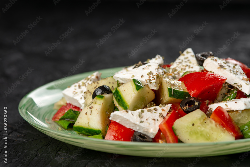 Greek salad with feta cheese, tomato, cucumber and olives on a black background Greek salad with feta cheese, tomato, cucumber and olives on a black background