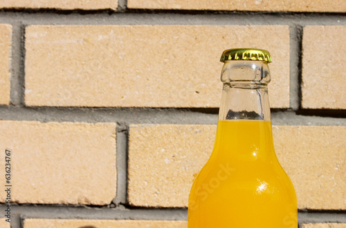 Glass Lemonade Bottle against the backdrop of a brick wall. Сloseup Photography for Banner, Promotion, Ptinting, Poster. Fresh and juicy non-alcoholic Summer drink With metal cup. photo