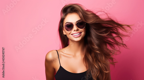 Beautiful happy young woman in sunglasses against pink background