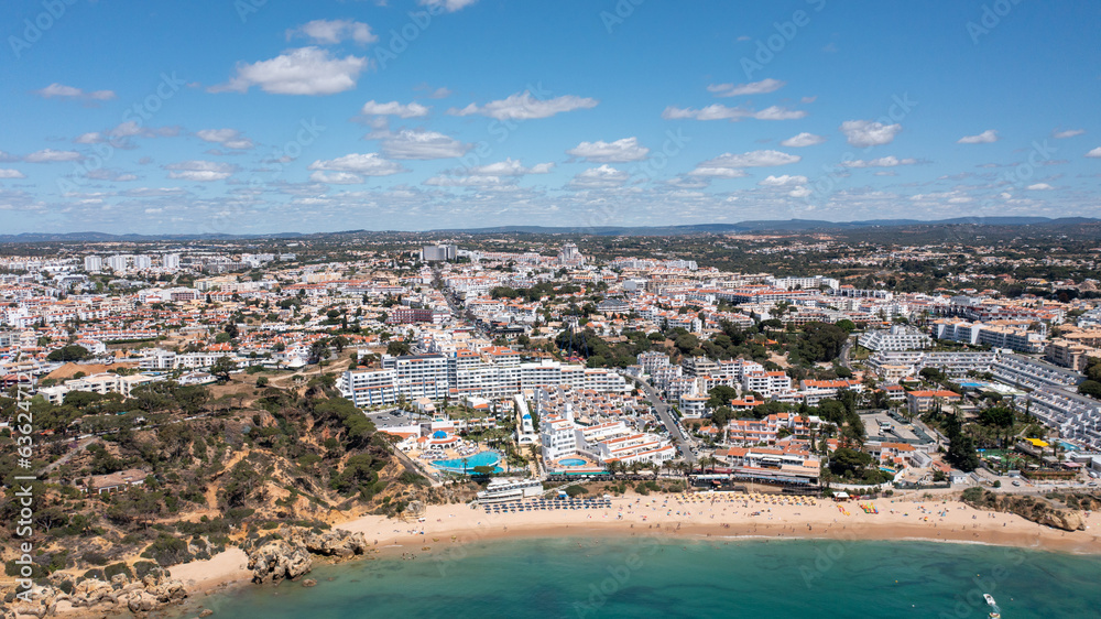 Aerial photo of the beautiful town in Albufeira in Portugal showing the Praia da Oura golden sandy beach, with hotels and apartment in the town, taken on a summers day in the summer time.