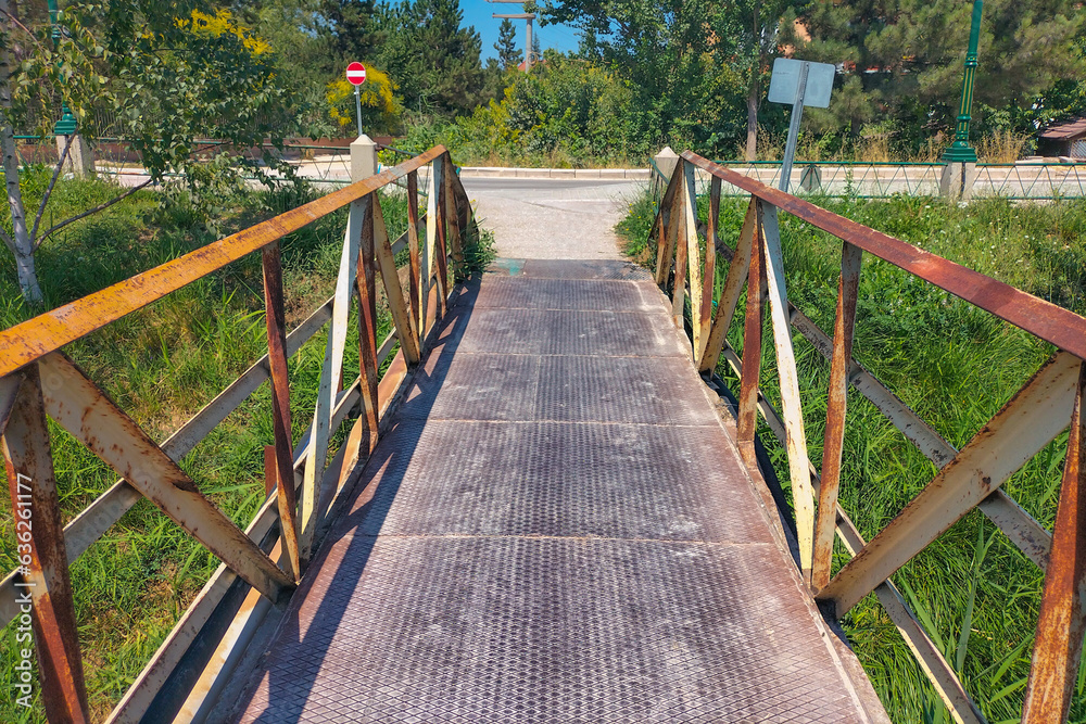 A metal pedestrian bridge connecting the two sides of the shore. Move to another area. The concept of the beginning of the path into the unknown