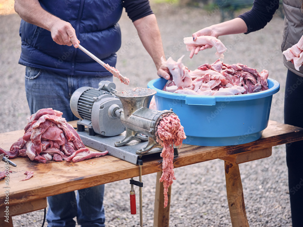 Crop man and woman grinding meat and fat in machine