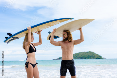 Couple playing surfboard on the beach in weekend activity, Sport extreme healthy lifestyle concept.
