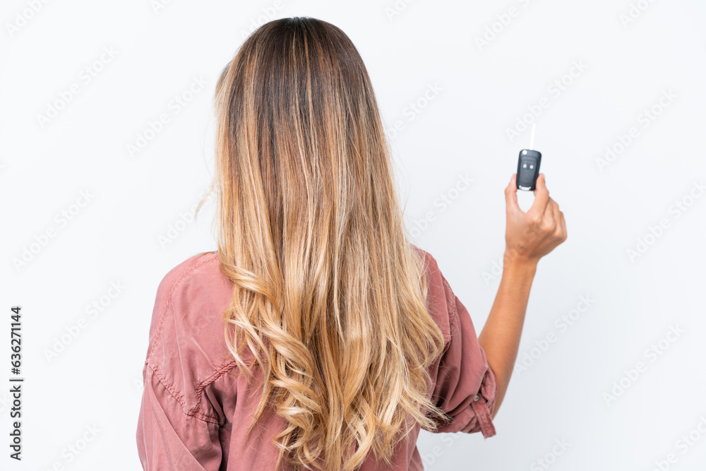Young pretty Uruguayan woman holding car keys isolated on white background in back position Young pretty Uruguayan woman holding car keys isolated on white background in back position