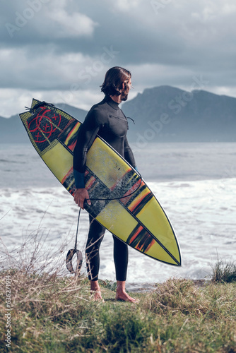 Canvas Print Fit male surfer admiring wavy sea after surfing