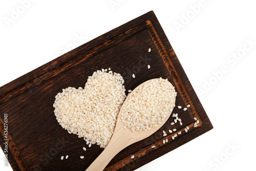 Calasparra rice or arroz calasparra in heart shape on brown wooden cutting board and spoon. Spanish processed white bomba rice ideal for paella. photo