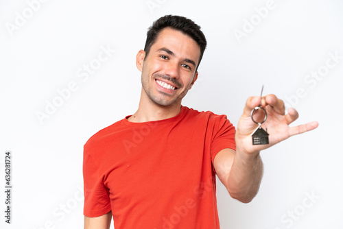 Young handsome man holding home keys isolated over isolated white background with happy expression