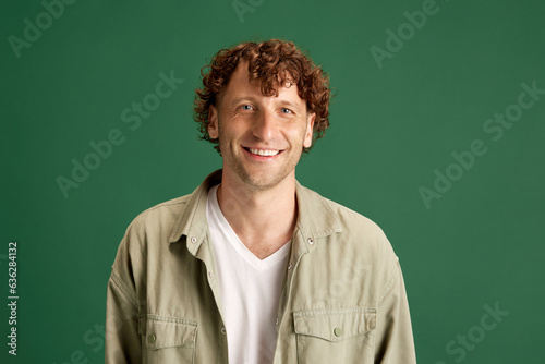 Happiness. Portrait of mature man with curly hair, in casual clothes posing with smile against green studio background. Concept of human emotions, facial expression, lifestyle, fashion, ad
