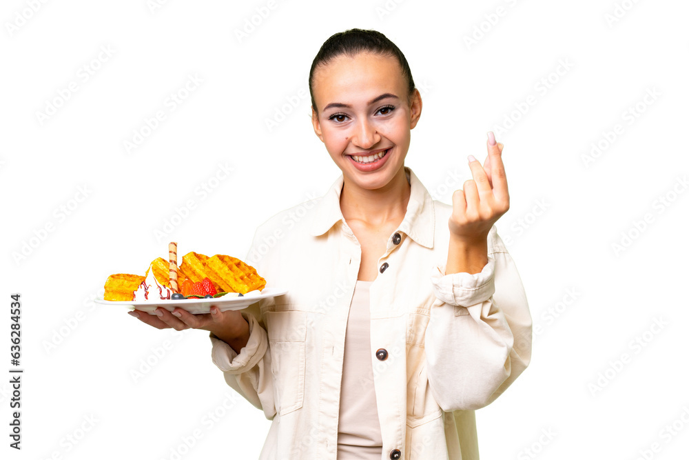 Young Arab woman holding waffles over isolated background making money gesture Young Arab woman holding waffles over isolated background making money gesture