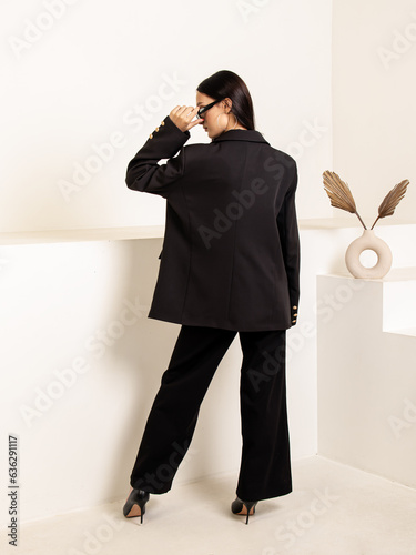 Woman in black oversize jacket. Classic women's suit for office, school, university, business meetings. Back view photo