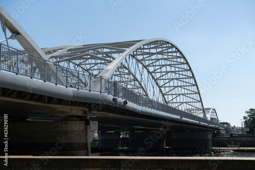 Railway bridge and a pedestrian and bicycle footbridge, connecting Grzegórzki with Zabłocie in Krakow, Poland. Train viaduct and walkway spanning over the Vistula River in Cracow, Wisła Kraków. © Longfin Media