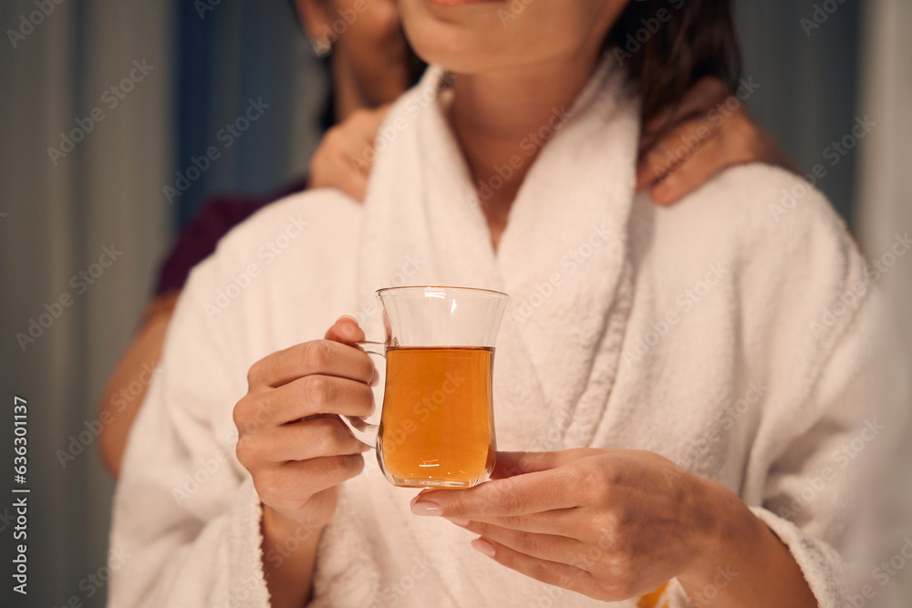 Female with herbal beverage in hands undergoing Thai massotherapy session Female with herbal beverage in hands undergoing Thai massotherapy session