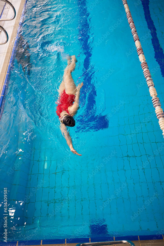 Experienced female swimmer practicing backstroke in water
