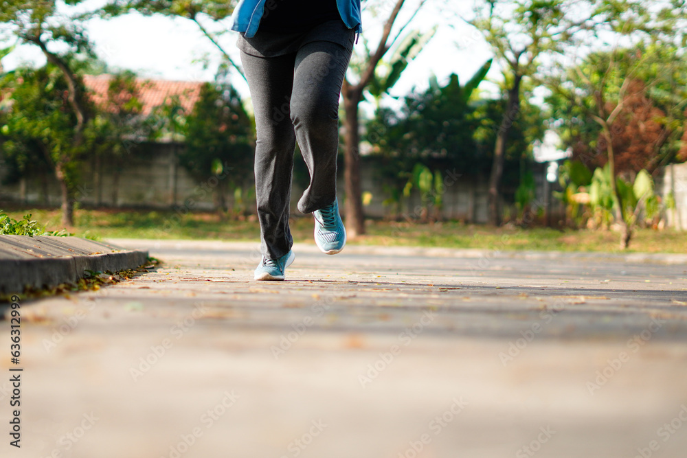 Obraz premium Sporty woman running on the road in the morning. Fitness and workout wellness concept.