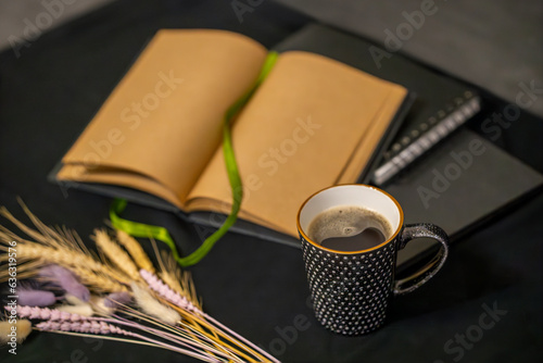 open notepad, cup of coffee and spikelets on a black background.