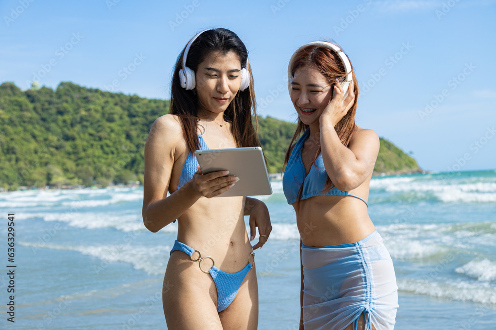 Young couple friends in summer bikini with couple listening to music enjoy playing tablet